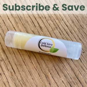 Purapolis Cold Sore Defense Daily Defense lip balm on a wooden tabletop, made with olive oil, lemon balm, organic coconut oil, shea butter, propolis, and sunflower oil for natural cold sore protection and daily lip care.